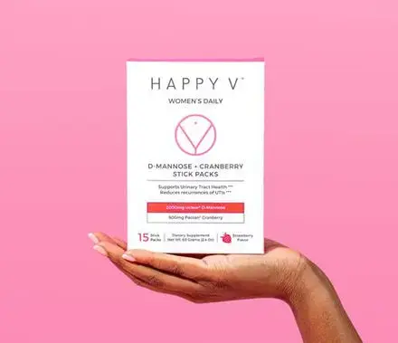 A woman's hand holding a box of Happy V's D-Mannose and Cranberry Stick Packs.